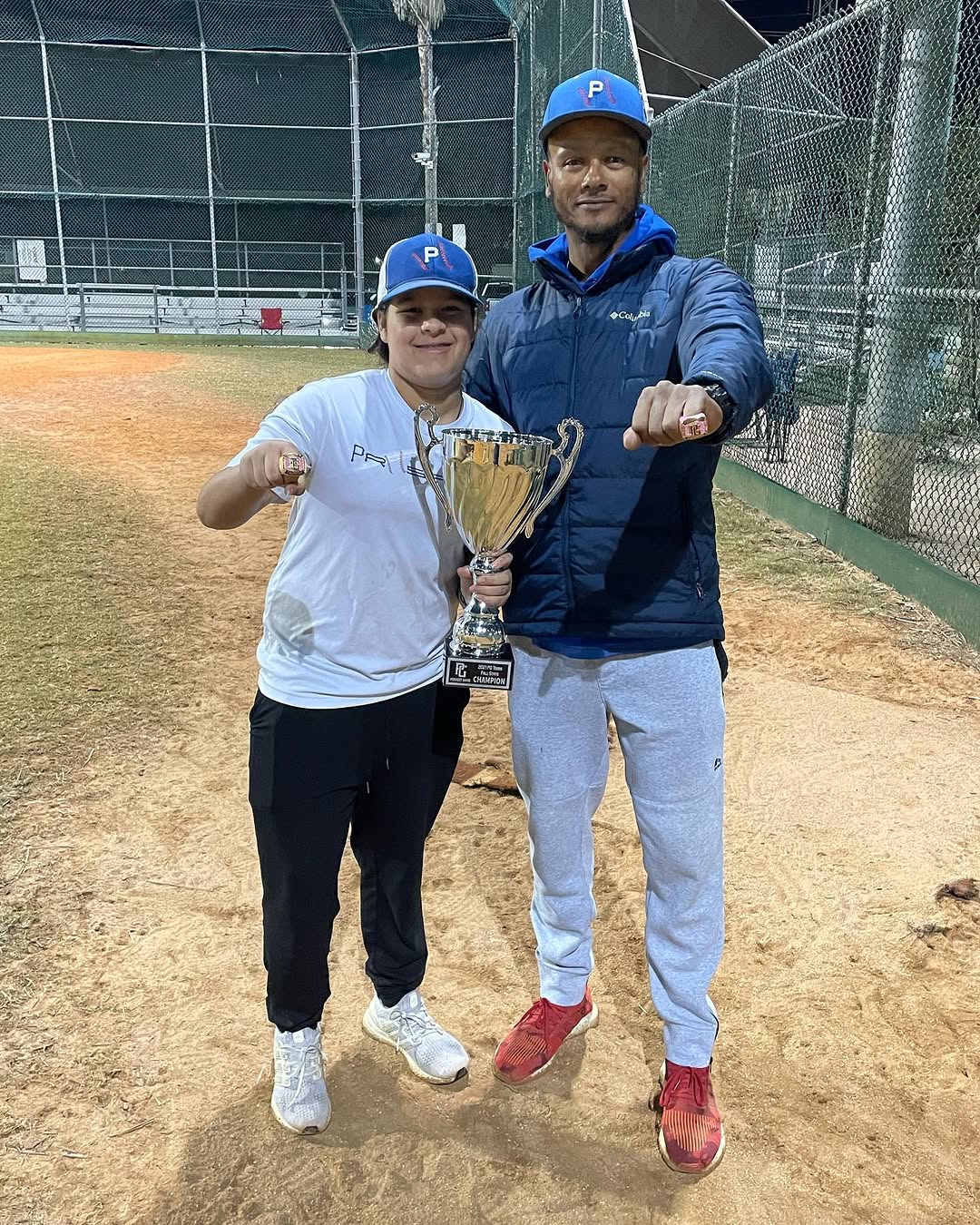 Coach C and Prospect player showing championship rings with trophy